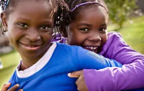 Black History Month events with smiling African American sisters hugging each other. 