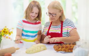 child and grandmother baking challah bread together