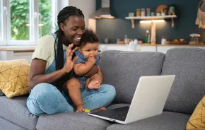 mom holding a baby waving to a computer call finding community online