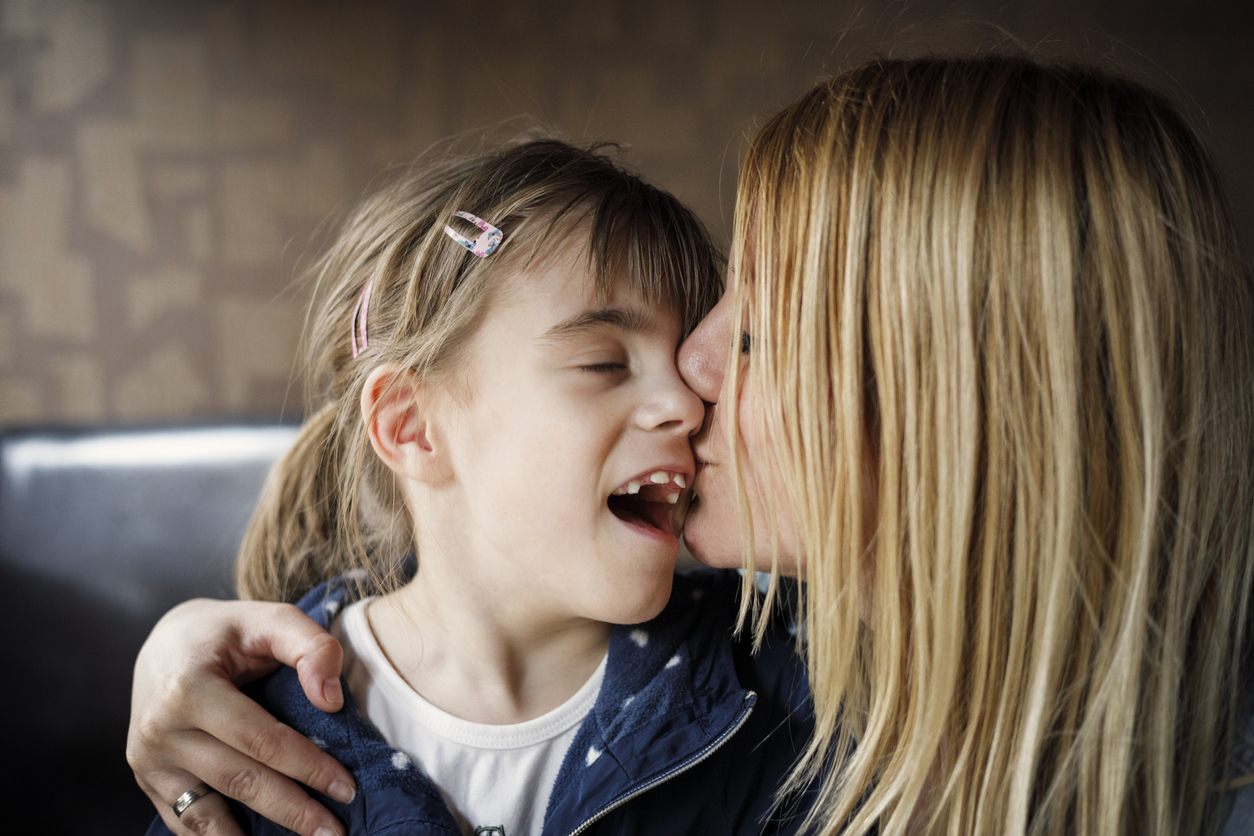 Mom kissing her child with special needs